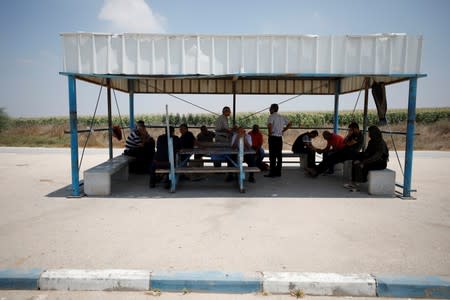 Palestinians gather beneath a shade as they wait on the Israeli side of Erez crossing, on the border with Gaza