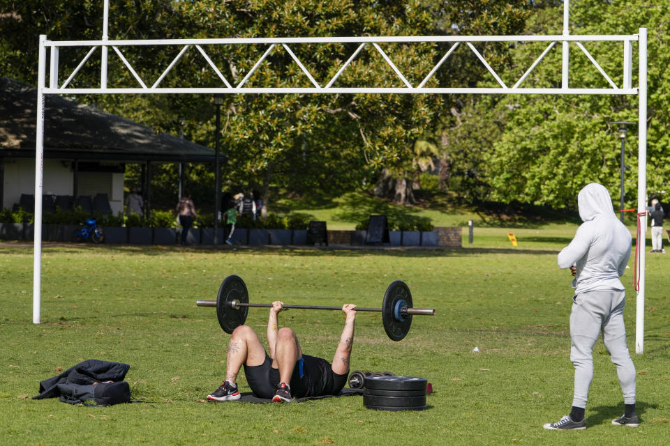 A personal trainer watches a client workout in a park in the eastern suburbs of Sydney Tuesday, Sept. 14, 2021. Personal trainers have turned a waterfront park at Sydney’s Rushcutters Bay into an outdoor gym to get around pandemic lockdown restrictions. (AP Photo/Mark Baker)