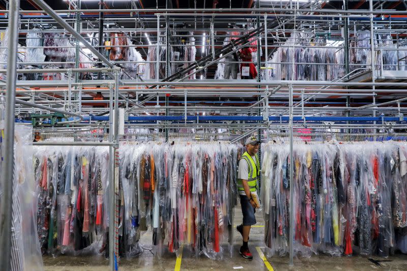 A person moves through clothing in the storage area at Rent the Runway's "Dream Fulfillment Center" in Secaucus, New Jersey