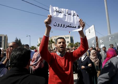A Palestinian teacher holds a sign that reads "Teacher's dignity, we will continue" during a protest demanding better pay and conditions, in the West Bank city of Ramallah March 7, 2016. REUTERS/Mohamad Torokman