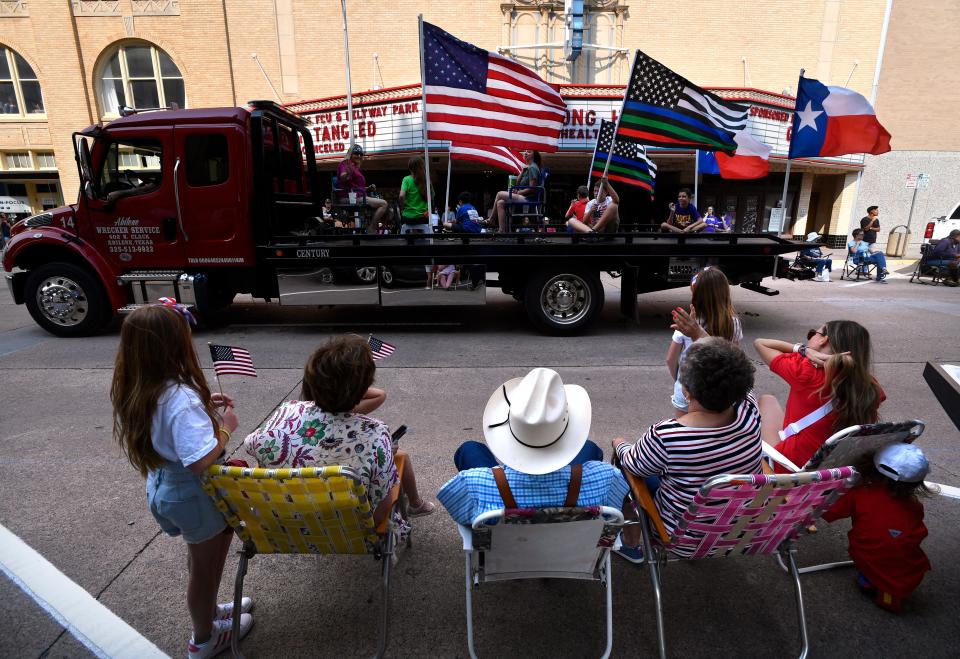 A family waves at a towing service truck displaying flags in front of the Paramount Theatre during the West Texas Fair & Rodeo Parade last year.