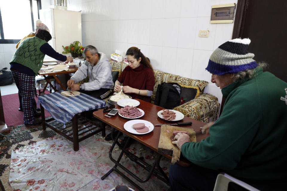 A family prepares sandwiches to feed displaced people following a devastating earthquake, at her house in the coastal city of Latakia, Syria, Friday, Feb. 10, 2023. The 7.8 magnitude earthquake that hit Turkey and Syria, killing more than 23,000 this week has displaced millions of people in war-torn Syria. The country's 12-year-old uprising turned civil war had already displaced half the country's pre-war population of 23 million before the earthquake. (AP Photo/Omar Sanadiki)