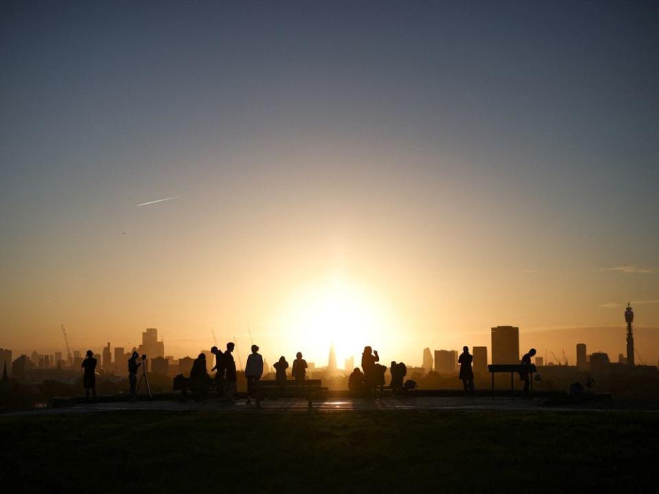 FILE PHOTO: People watch the sunrise behind the city skyline from the top of Primrose Hill in London