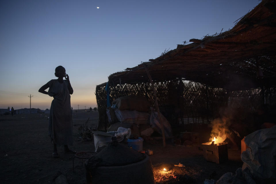 A Tigrayan refugee woman who fled the conflict in the Ethiopia's Tigray talks on a mobile phone in front of her shelter at Hamdeyat Transition Center near the Sudan-Ethiopia border, eastern Sudan, March 16, 2021. (AP Photo/Nariman El-Mofty)