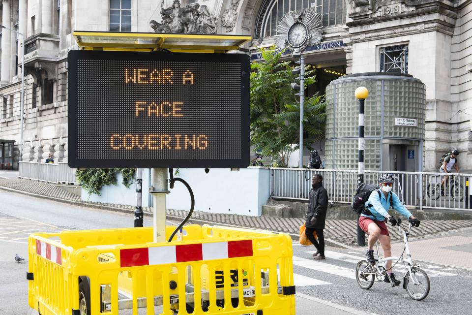 A cyclist wearing a face covering rides past a digital display outside Waterloo Station informing the public to wear a face covering, after the Government has made it mandatory to wear face coverings on all public transport and retail outlets, Waterloo, London. Picture date: Friday 24th July 2020. Photo credit should read: David Jensen/EMPICS Entertainment