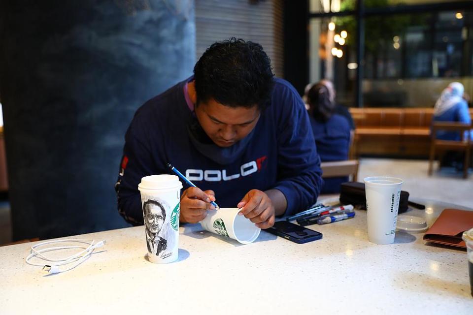 Luqman Hakim in his zone as he draws portraits on various Starbucks cups. His medium extends to paper cups, reusable cups and even canvas. — Picture courtesy of Starbucks Malaysia