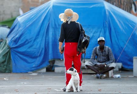 A woman looks as a migrant waits to be identified by Italian police in a camp set by the Baobab aid group in Rome, Italy July 12, 2018. Picture taken July 12, 2018. REUTERS/Yara Nardi