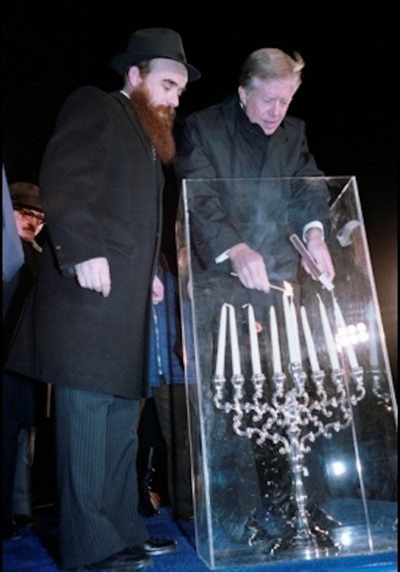 President Jimmy Carter lights a menorah at the White House in 1979 as a rabbi looks on.