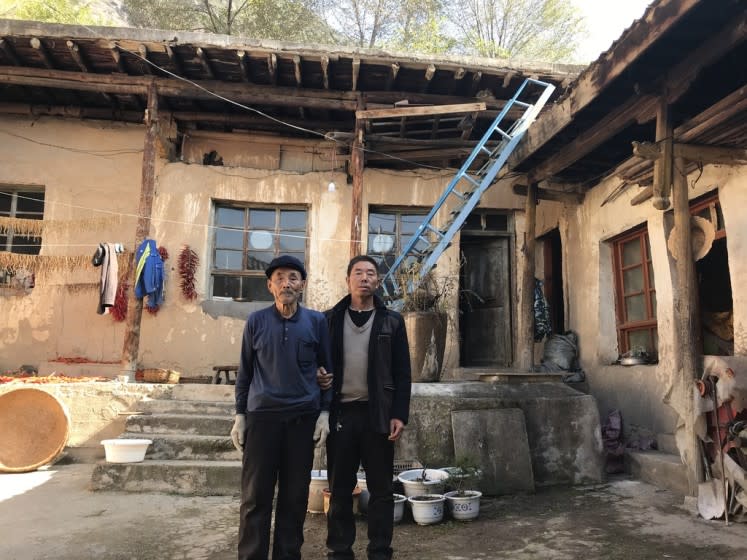 Yang Qinglai and his son Yang Jiacun stand in their home in Lianghekou, Gansu province, on Nov. 11, 2020. They are among a handful of families still living here after most of the village was relocated to new apartments as part of China's poverty elimination drive in 2018.