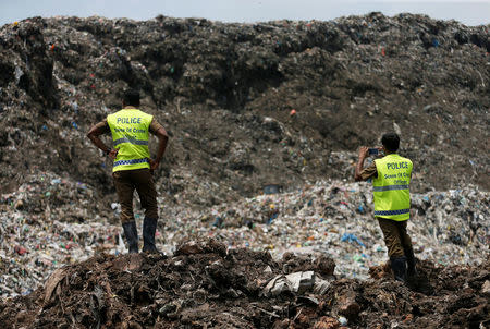 Sri Lankan crime police officers take pictures of the garbage dump during a rescue mission after a garbage dump collapsed and buried dozens of houses in Colombo, Sri Lanka April 16, 2017. REUTERS/Dinuka Liyanawatte