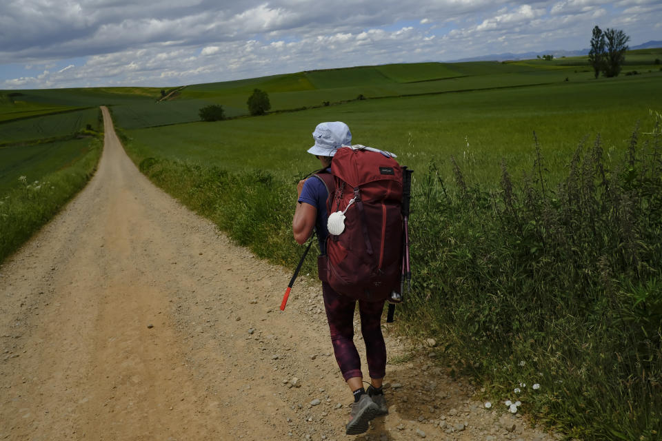 A pilgrim walks during a stage of "Camino de Santiago" or St. James Way, near to Santo Domingo de La Calzada, northern Spain, Tuesday, May 31, 2022. Over centuries, villages with magnificent artwork were built along the Camino de Santiago, a 500-mile pilgrimage route crossing Spain. Today, Camino travelers are saving those towns from disappearing, rescuing the economy and vitality of hamlets that were steadily losing jobs and population. “The Camino is life,” say villagers along the route. (AP Photo/Alvaro Barrientos)