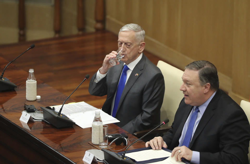 U.S. Defense Secretary James Mattis, left, drinks water as U.S. Secretary of State Mike Pompeo, makes his statement after the so called "2+2" meeting in New Delhi, India, Thursday, Sept. 6, 2018. Pompeo and Mattis held long-delayed talks Thursday with top Indian officials, looking to shore up the alliance with one of Washington's top regional partners. (AP Photo/Manish Swarup)