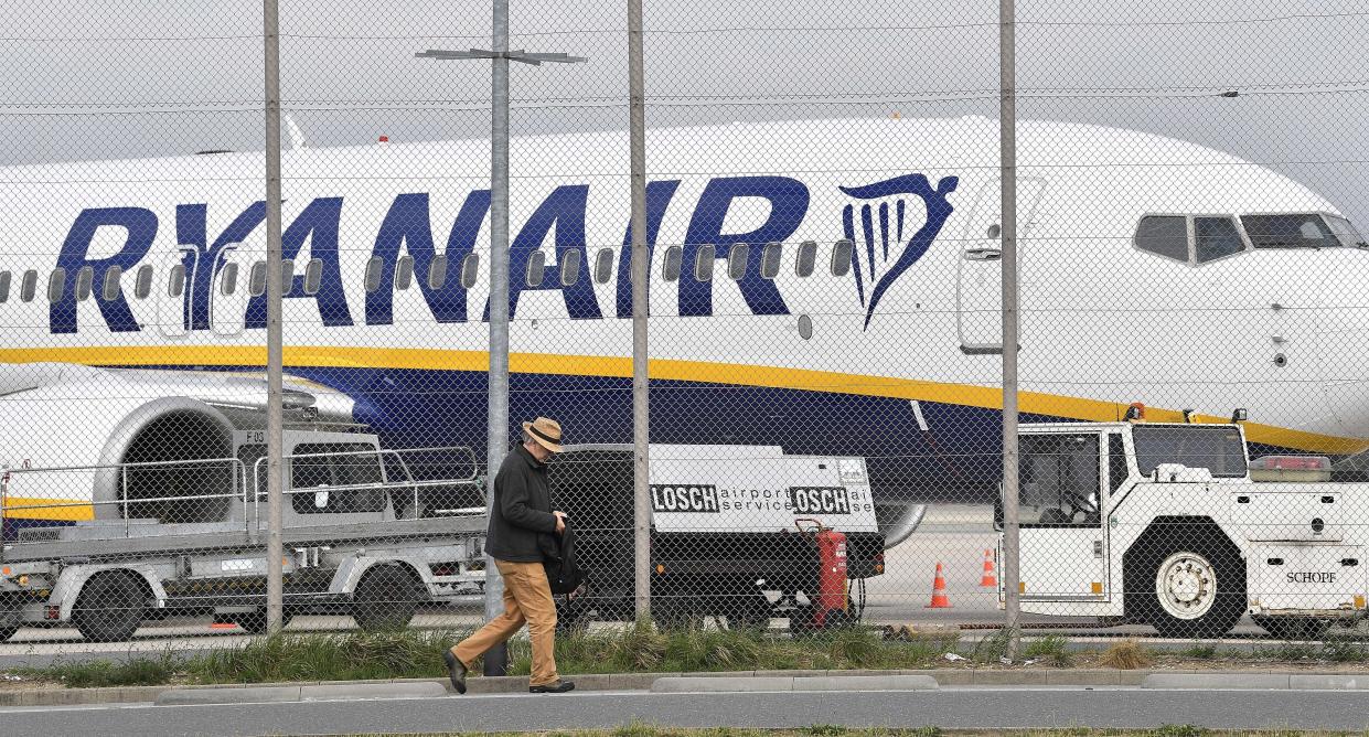 A man passes a parking Ryanair jetplane at the airport in Weeze, Germany, Wednesday, Sept. 12, 2018. Ryanair is canceling dozens of flights after pilots and flight attendants started a one-day strike over pay and conditions. (AP Photo/Martin Meissner)