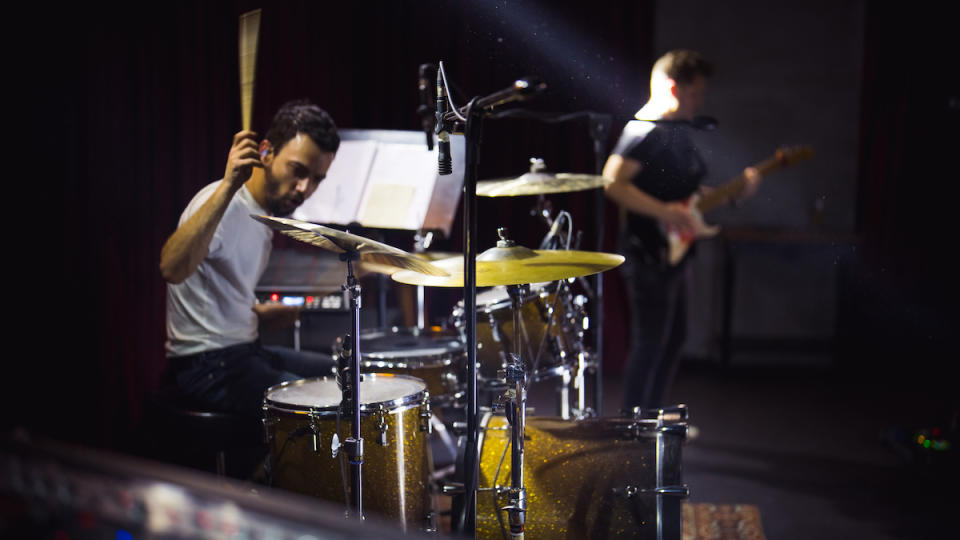 Man playing a yellow drum kit live on stage