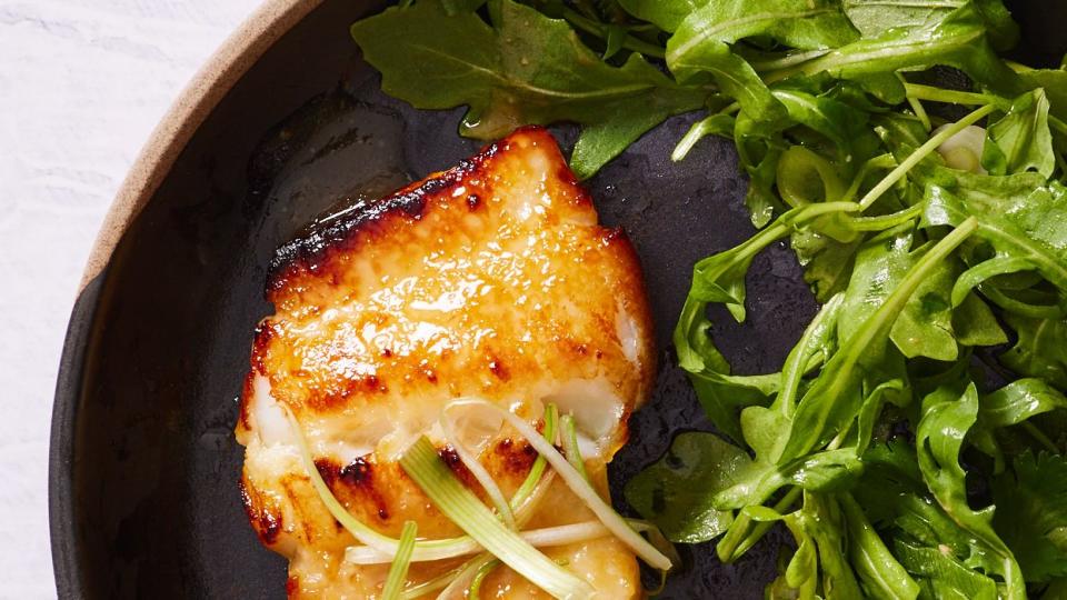 miso marinated chilean sea bass with wilted arugula on a plate