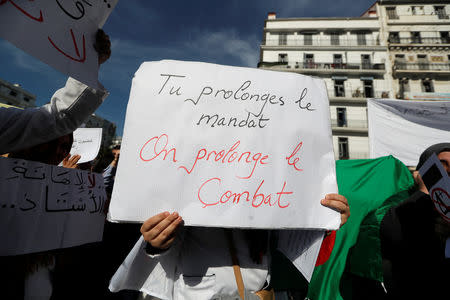 A demonstrator carries a sign as teachers and students take part in a protest demanding immediate political change in Algiers, Algeria March 13, 2019. The sign reads: "You extend your term, we extend our combat". REUTERS/Zohra Bensemra