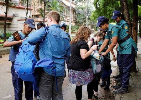 Police officers search the bags of unidentified foreigners on the road leading to the Holey Artisan Bakery and the O'Kitchen Restaurant after gunmen attacked, in Dhaka, Bangladesh, July 3, 2016. REUTERS/Mohammad Ponir Hossain