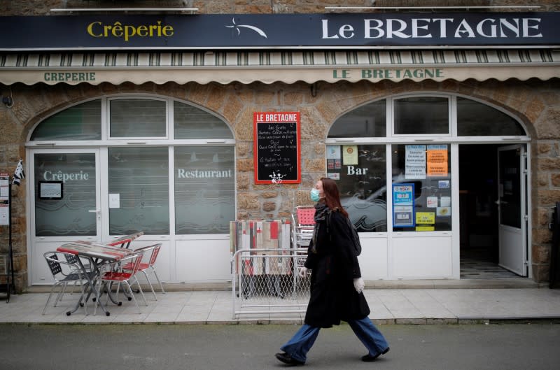 A woman, wearing a protective face mask, walks in a street in Saint-Jacut-de-la-Mer in Brittany