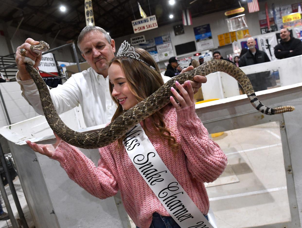 Sweetwater Jaycee Dennis Cumbie drapes a western diamondback rattlesnake around Macy Newberry, a junior at Sweetwater High School on Friday. Macy won his year's Miss Snake Charmer pageant and said that at 10 a.m. Saturday, she will be skinning snakes at Nolan County Coliseum at the 64th World's Largest Rattlesnake Roundup.