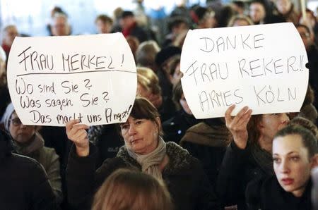 Women hold up placards that read "Mrs. Merkel: Where are you? What are you saying? This worries us!" and "Thanks (Cologne mayor Henriette) Reker!! Poor Cologne" (R) during a protest in front of the Cologne Cathedral, Germany, January 5, 2016. REUTERS/Wolfgang Rattay