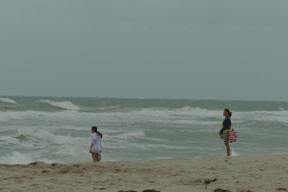 A woman observes two girls as they dip their feet in the water in Miami Beach, Florida, on Friday, Dec. 15, 2023.