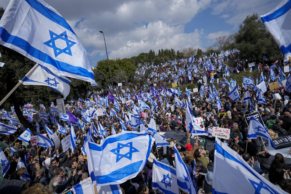 FILE - Israelis wave national flags during a protest against plans by Prime Minister Benjamin Netanyahu's new government to overhaul the judicial system, outside the Knesset, Israel's parliament, in Jerusalem, Monday, Feb. 13, 2023. (AP Photo/Ohad Zwigenberg, File)