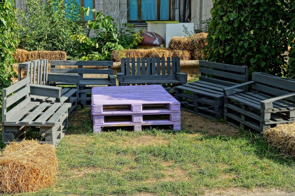 grey benches and a purple table made of wooden pallets in garden