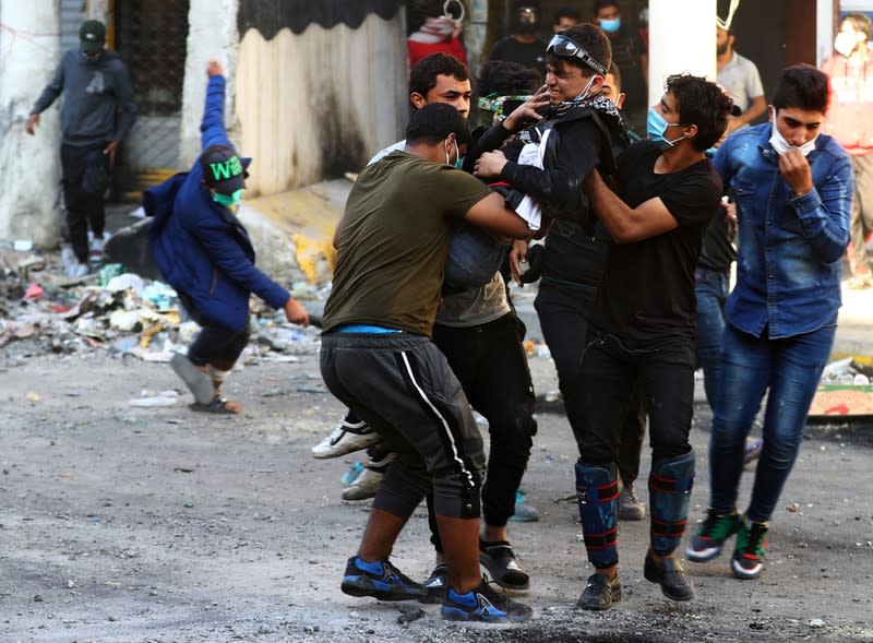 Demonstrators carry away a boy affected by tear gas during ongoing anti-government protests in Baghdad