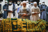 Varias personas rezan frente al cadáver de Mohammad Altaf, que murió de COVID-19, en la Funeraria Musulmana Al-Rayan el domingo 17 de mayo de 2020, en el distrito de Brooklyn, en Nueva York. Diversas familias han tenido que homenajear a sus muertos desde lejos y en pequeños grupos en los actuales tiempos del distanciamiento social por la pandemia. (AP Foto/John Minchillo)