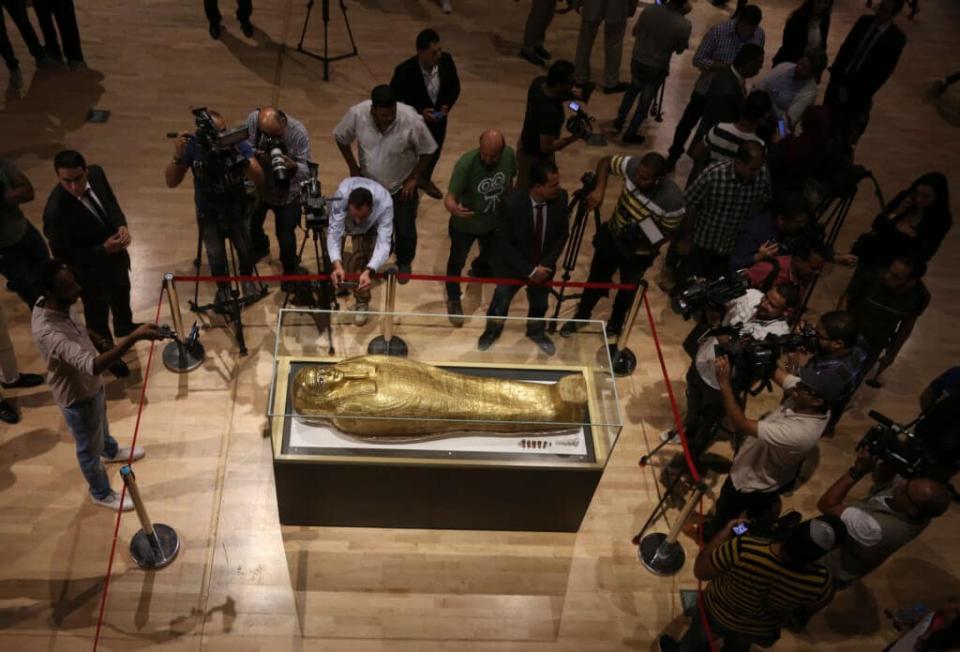 IMAGE DOES NOT DEPICT LOOTED ITEMS DESCRIBED IN STORY. Journalists gather around the golden coffin that once held the mummy of Nedjemankh, a priest in the Ptolemaic Period some 2,000 years ago, at the National Museum of Egyptian Civilization, in Old Cairo, Egypt, Tuesday, Oct. 1, 2019. Egypt is displaying the gilded ancient coffin returned to the country last week from New York’s Metropolitan Museum of Art after U.S. investigators determined to be a looted antiquity. (AP Photo/Mahmoud Bakkar)