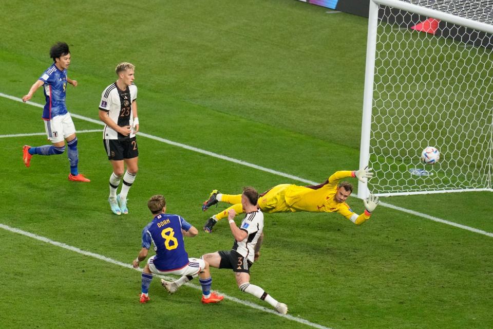 Japan's Ritsu Doan, bottom left, scores his side goal during the World Cup group E football match between Germany and Japan, at the Khalifa International Stadium in Doha, Qatar, Wednesday, Nov. 23, 2022. (AP Photo/Ricardo Mazalan)