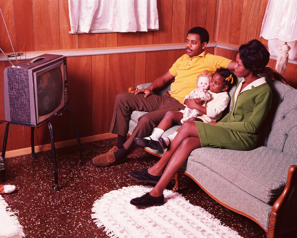 A family is sitting in the living room watching TV