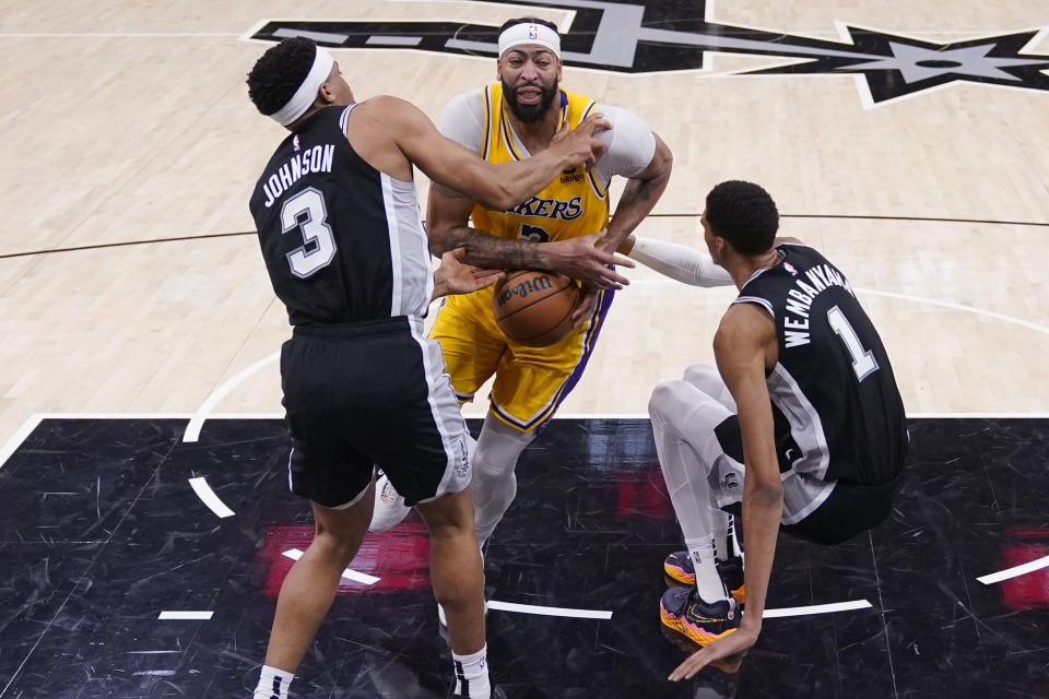 Los Angeles Lakers forward Anthony Davis, center, is fouled by San Antonio Spurs center Victor Wembanyama (1) as he drives into the lane during the second half of an NBA basketball game in San Antonio, Wednesday, Dec. 13, 2023. (AP Photo/Eric Gay)