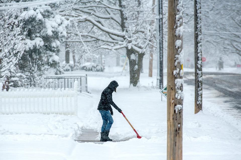 Julie Ahlgren tries to keep the falling snow off her shoveled driveway Wednesday, Jan. 25, 2023 in Washington.