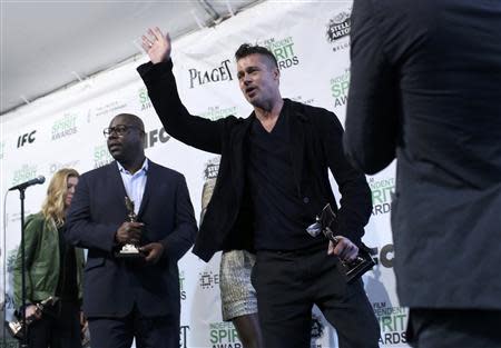 Producer Brad Pitt (C) waves as he leaves the press room with Best Director winner Steve McQueen (L) after they won the Best Feature award for the film "12 Years a Slave" at the 2014 Film Independent Spirit Awards in Santa Monica, California March 1, 2014. REUTERS/Robert Galbraith