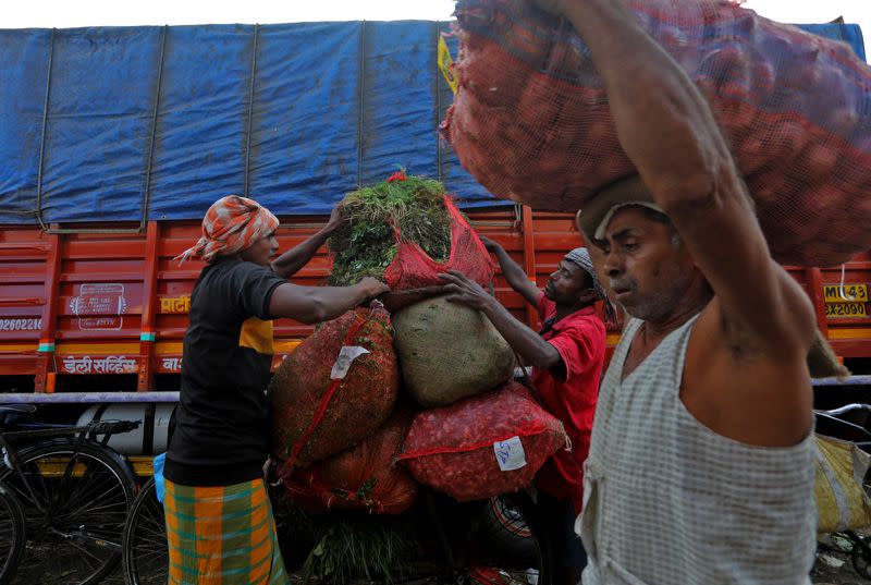 Labourers load vegetables on a bicycle at a fruit and vegetable wholesale market in Mumbai