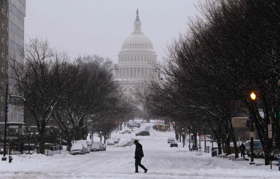 A pedestrian walks across New Jersey Avenue in front of the U.S. Capitol building on the largely deserted streets of Washington as a major snow storm hits the Washington area