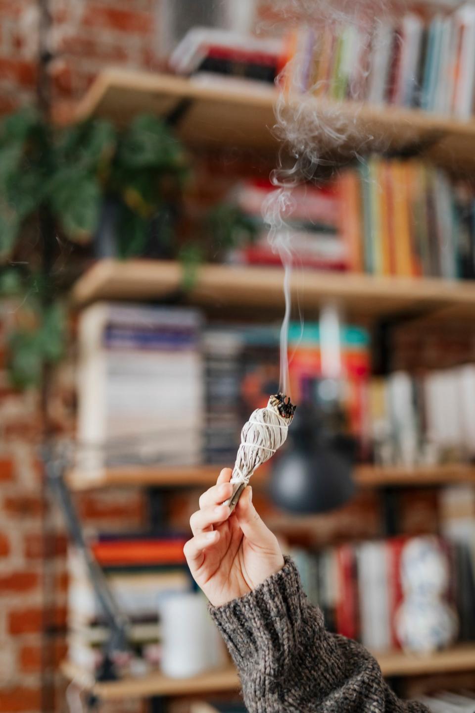 <h1 class="title">Woman burning sage smudge to cleanse the house</h1><cite class="credit">Photo: Rawpixel/Getty Images</cite>