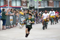 FILE - Green Bay Packers tight end Josiah Deguara, third from right, rides a young fan's bike as the fan takes off running with Deguara's helmet during the team's NFL football training camp July 27, 2022, in Green Bay, Wisc. (Samantha Madar/The Post-Crescent via AP, File)