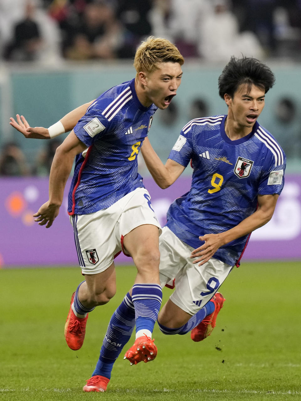 Japan's Ritsu Doan, left, celebrates with teammate Kaoru Mitoma scoring his side's first goal against Spain during a World Cup group E soccer match at the Khalifa International Stadium in Doha, Qatar, Thursday, Dec. 1, 2022. (AP Photo/Eugene Hoshiko)