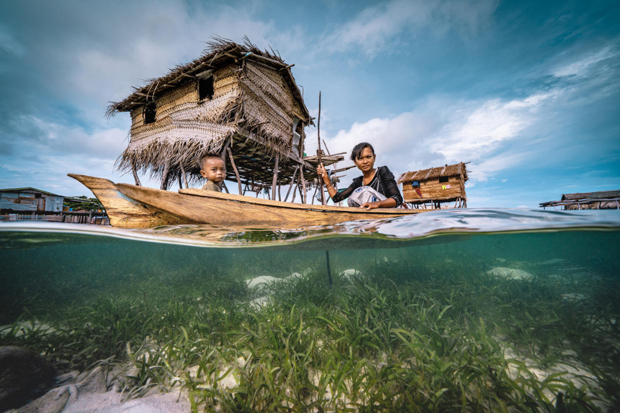 Una mujer Bajau rema en una canoa de madera junto a su hijo en el pueblo flotante. (Getty Images)