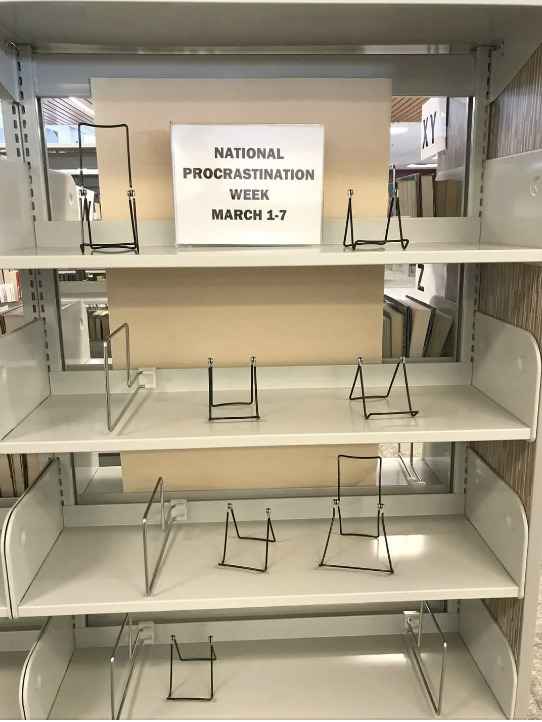 Sign on empty bookstore shelf reads "National Procrastination Week March 1-7"