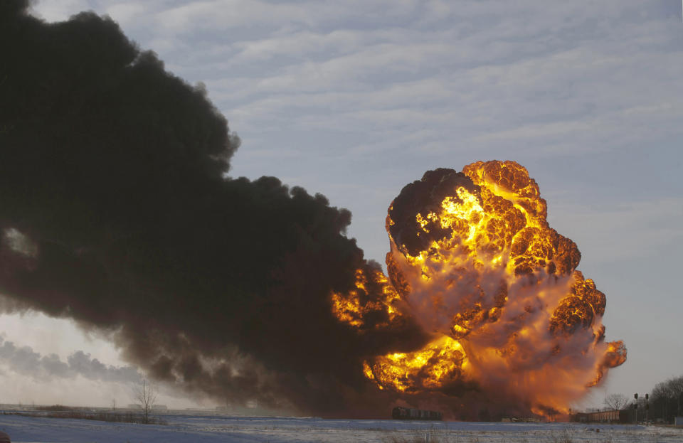 FILE - In this Dec. 30, 2013 file photo, a fireball goes up at the site of an oil train derailment near Casselton, N.D. The Trump administration vastly understated the potential benefits of installing more advanced brakes on trains that haul explosive fuels when it cancelled a requirement for railroads to begin using the equipment. A government analysis used by the administration to justify the cancellation omitted up to $117 million in potential reduced damages from using electronic brakes. Department of Transportation officials acknowledged the error after it was discovered by The Associated Press during a review of federal documents but said it would not have changed their decision. (AP Photo/Bruce Crummy, File)