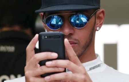 Mercedes Formula One driver Lewis Hamilton of Britain looks at a phone in his team garage at the Marina Bay street circuit before the third practice session of the Singapore F1 Grand Prix September 19, 2015. REUTERS/Edgar Su