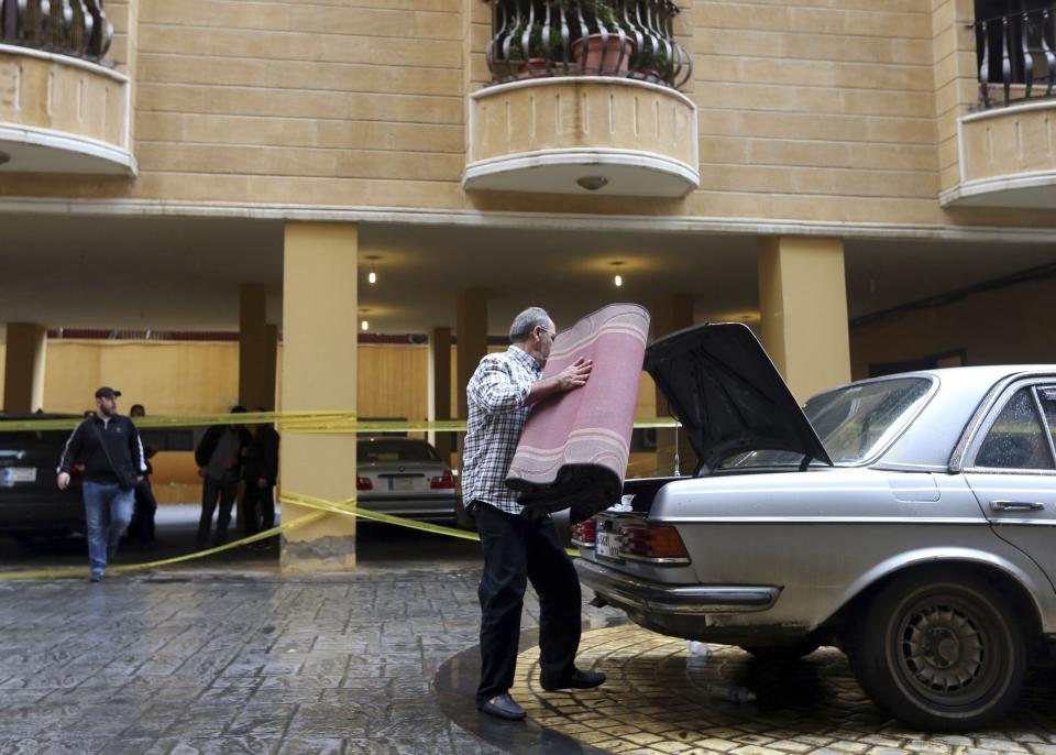 A man puts a carpet on the back of a car near the crime scene where commander Hasan al-Laqqis was killed in the southern Hadath district in Beirut December 4, 2013. Lebanon's Shi'ite militant Hezbollah group said on Wednesday al-Laqis was killed outside his Beirut home in an overnight attack it blamed on Israel. Israel denied any role in the killing, which Hezbollah said took place at around midnight in the southern Hadath district of the Lebanese capital. REUTERS/Hasan Shaaban (LEBANON - Tags: POLITICS CIVIL UNREST)