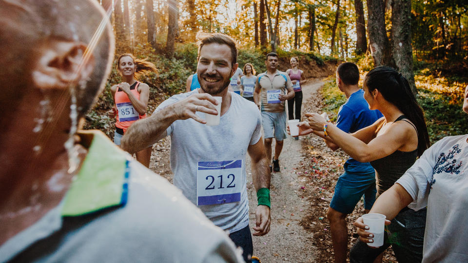 Runners in a trail race accepting cups of water from the marshals.