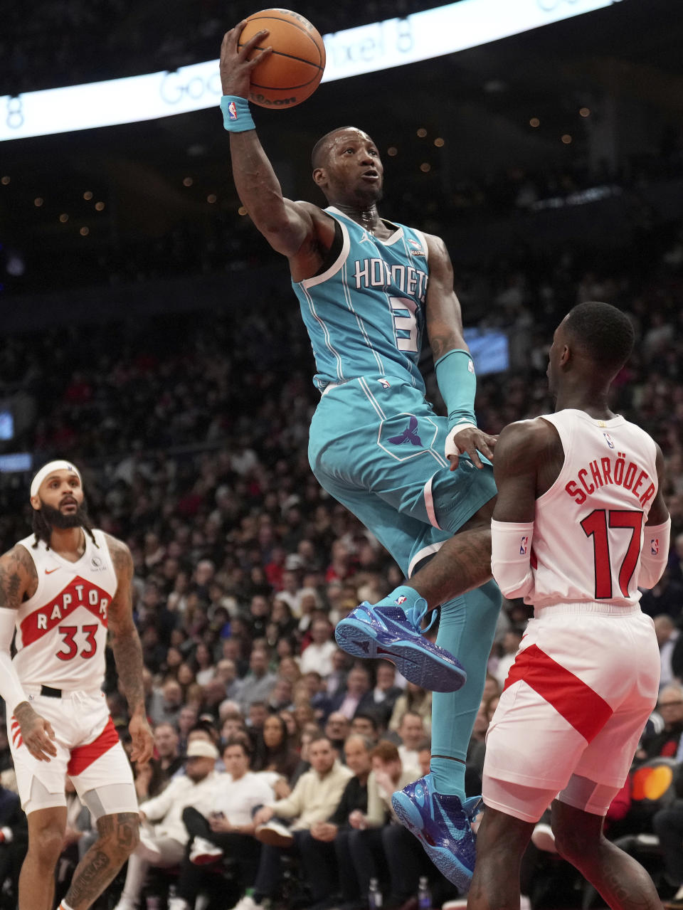 Charlotte Hornets guard Terry Rozier (3) drives into Toronto Raptors guard Dennis Schroder (17) as teammate Gary Trent Jr. (33) looks on during first half of an NBA basketball game in Toronto, Monday, Dec. 18, 2023. (Nathan Denette/The Canadian Press via AP)