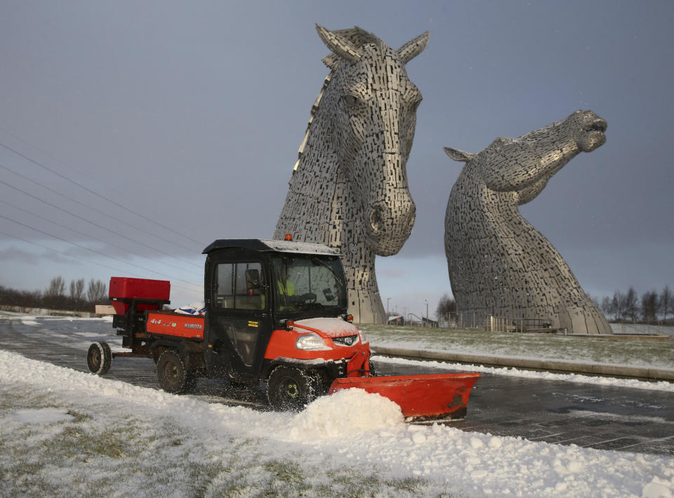 A worker uses a vehicle to clear snow on a pathway at the Kelpies near Falkirk in Scotland, Monday, Feb. 8, 2021. (Andrew Milligan/PA via AP)