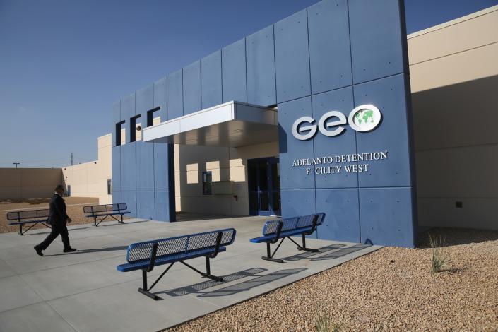 A man walks into a building with a sign that says Geo Adelanto Detention Facility West