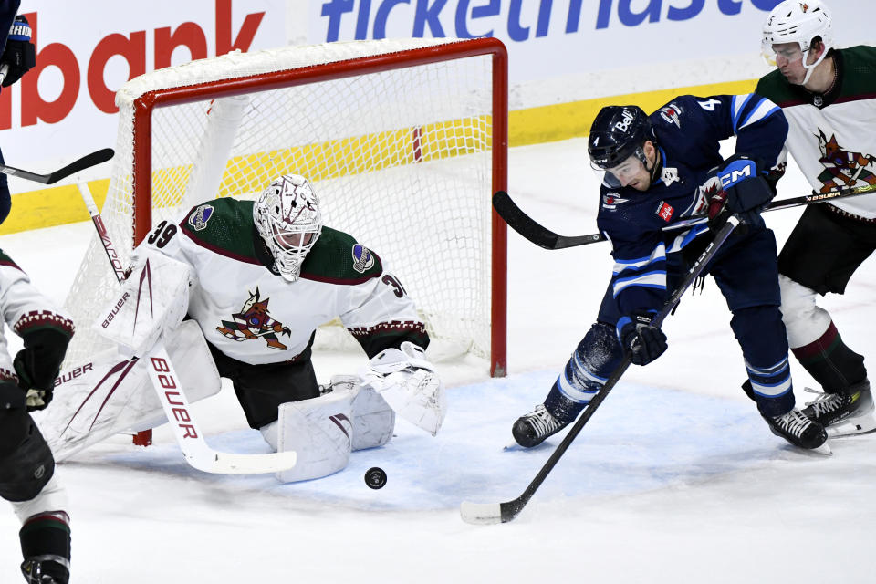 Arizona Coyotes goaltender Connor Ingram (39) makes a save on Winnipeg Jets defenseman Neal Pionk (4) during the first period of an NHL hockey game in Winnipeg, Manitoba on Sunday, Feb. 25, 2024. (Fred Greenslade/The Canadian Press via AP)